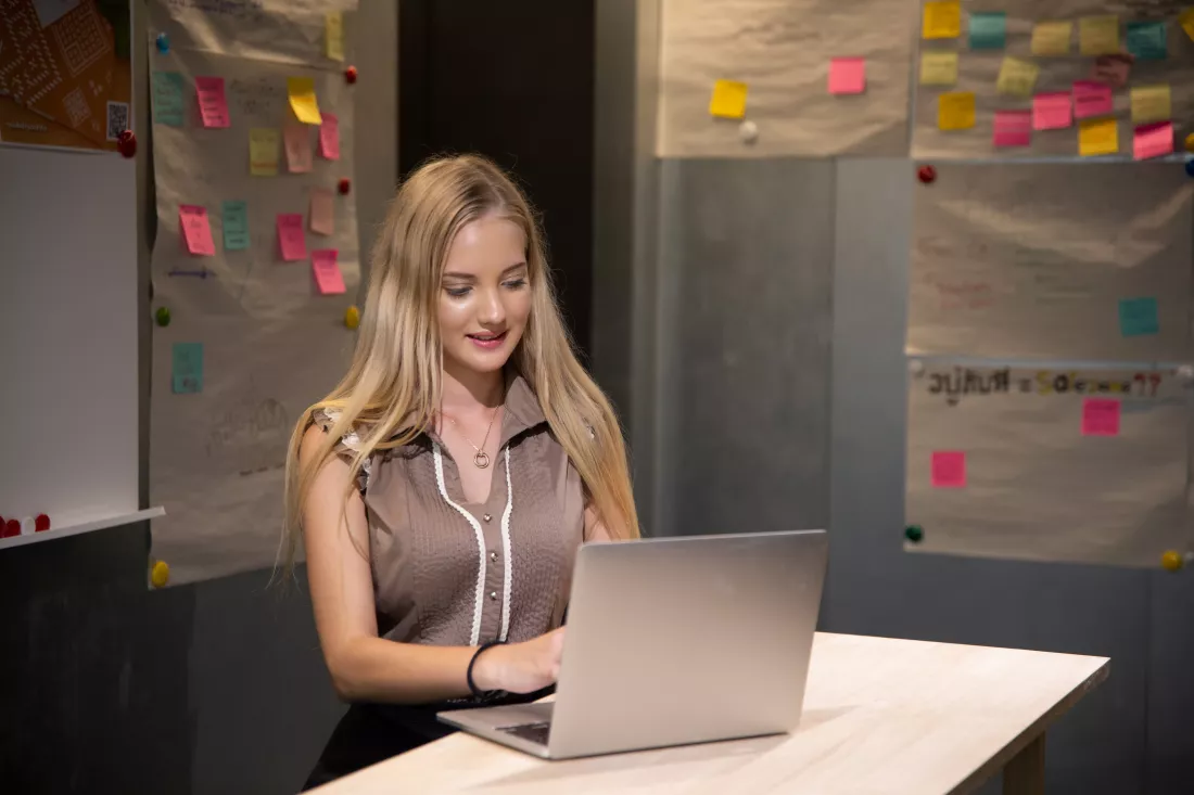 happy-woman-uses-laptop-work-communicate-with-friends-workplace